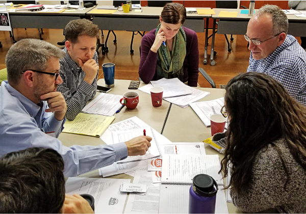 Five employees collaborating around table