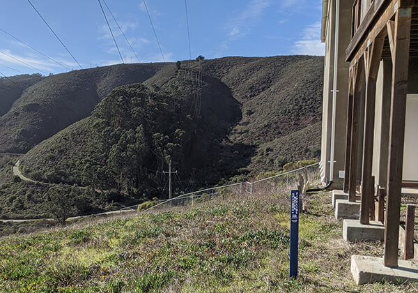 View of hillside showing the route a pipeline will go from a post on one hill to the top of a ridge on the next hill