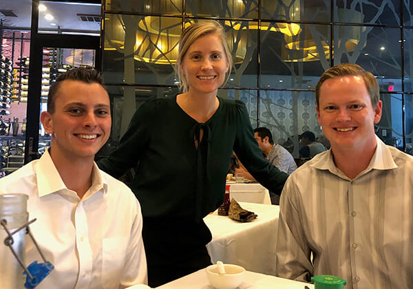 Three Young Professional group members at a restaurant posing and smiling
